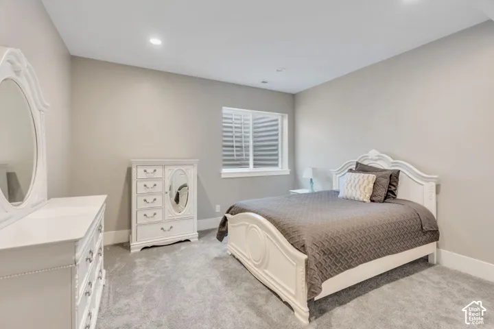 Recessed lighting, light gray wall paint, gray carpet flooring, and a window with blinds