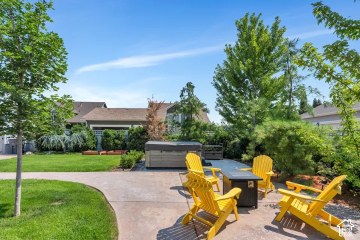 Expansive backyard featuring a hot tub, concrete patio, and a dedicated fire pit area