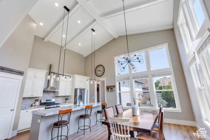 Open-concept kitchen and dining area featuring vaulted ceilings with skylights, recessed lighting, and white shaker cabinetry