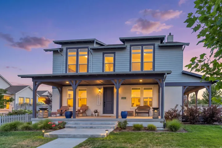 Two-story residence featuring a covered front porch, multiple windows, and a combination of siding and stucco exterior