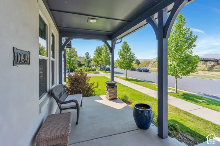 Covered front porch with an overhead light fixture, featuring dark-toned support columns and a concrete surface
