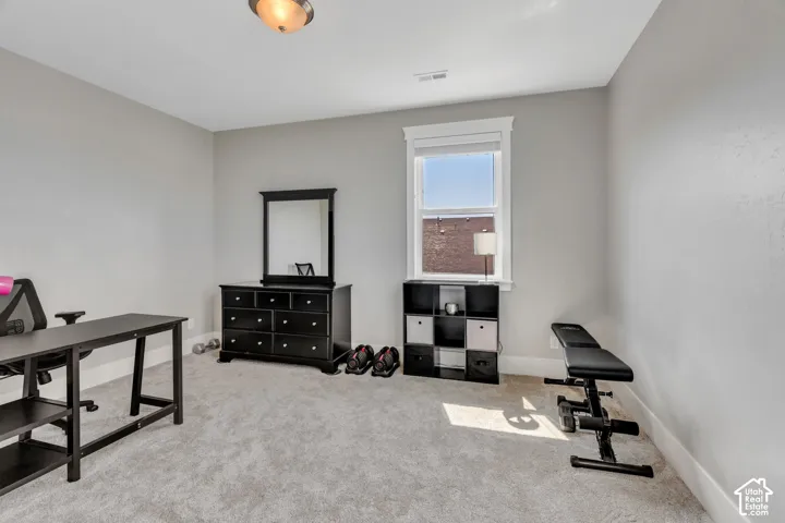 Versatile secondary bedroom or home office space featuring carpet flooring, abundant natural light from a large window, black cabinetry with mirrored accent, and recessed ceiling lighting