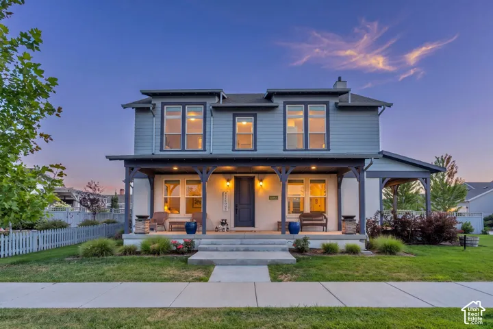 Modern farmhouse exterior featuring a two-story design with board-and-batten siding, black-trimmed multi-pane windows, and a covered front porch with decorative columns
