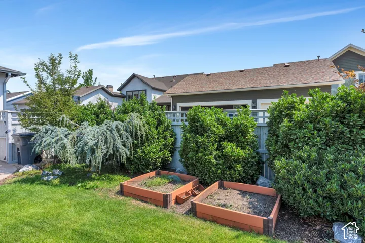 Manicured lawn with mature landscaping, featuring two raised garden beds and a privacy fence