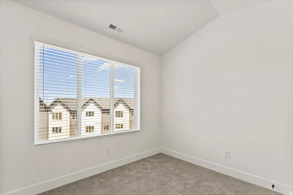 Wall-to-wall carpeting and a large window with blinds