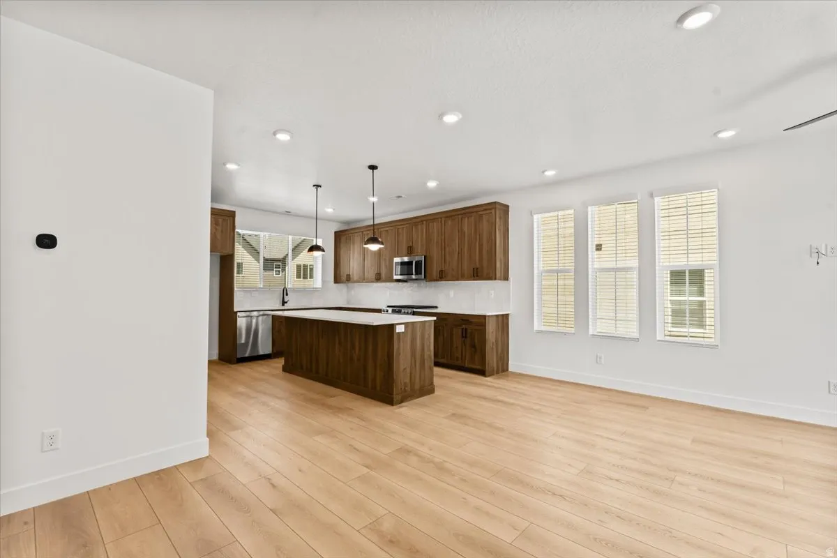 Open-concept living space with light wood-finish flooring, recessed lighting, and ample natural light from multiple windows
