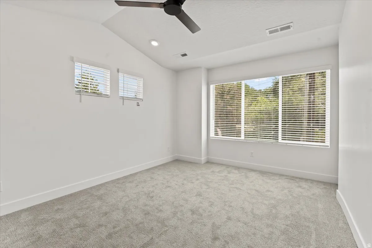 Vaulted ceiling with a ceiling fan, recessed lighting, and expansive windows