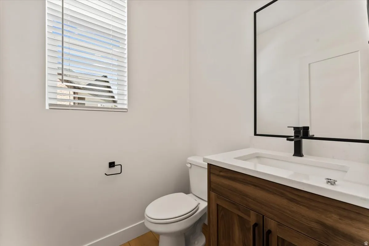 Wood-finish vanity with white countertop and integrated sink, complemented by a matte black faucet and framed mirror