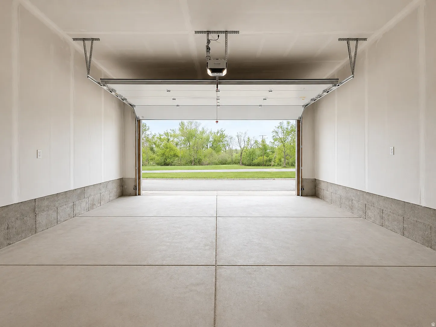Concrete slab flooring, concrete block wainscoting, and an overhead garage door with opener