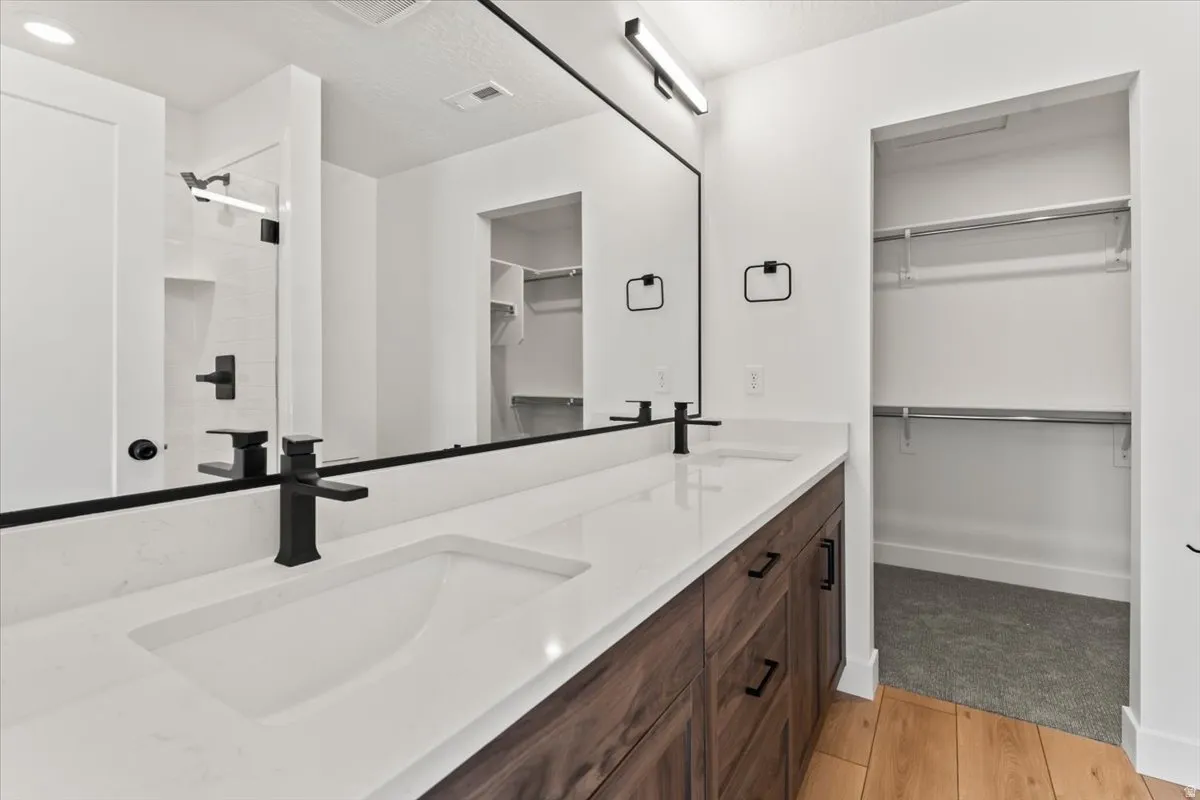 Dual vanity with integrated sinks, quartz countertop, dark wood-finish cabinetry, and matte black fixtures