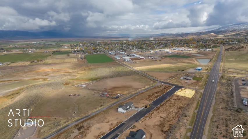 Expansive rural landscape with distant mountainous terrain, a developed road system, and visible residential structures