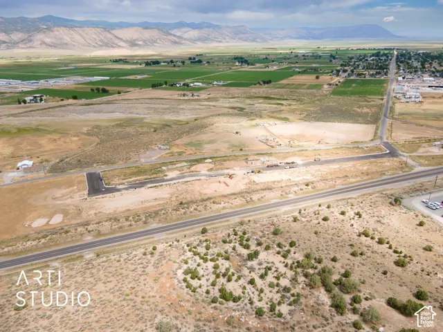 Expansive land parcel featuring established roadways, mountainous backdrop, and agricultural zones