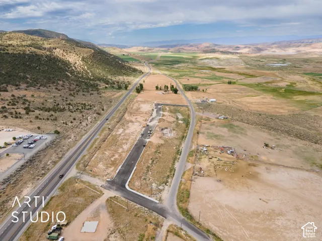 Expansive undeveloped land featuring a paved roadway, mountainous terrain, and distant water features