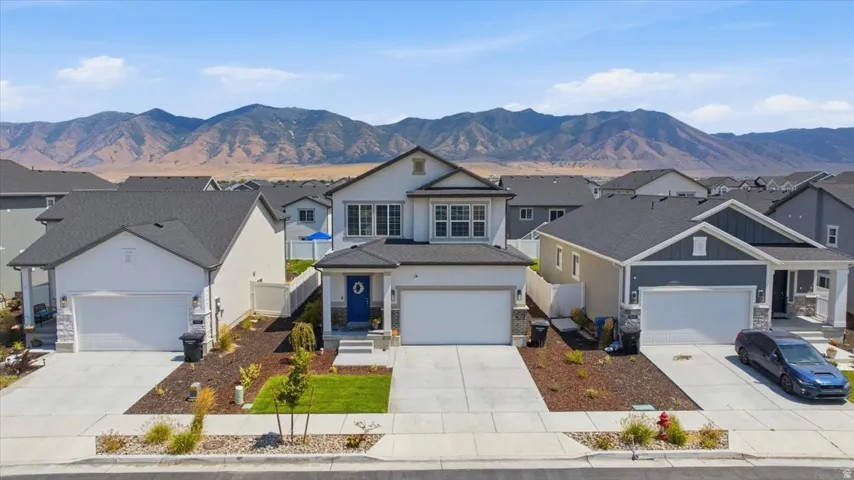 Contemporary residence featuring a two-car garage, manicured lawn, and mountain scenery