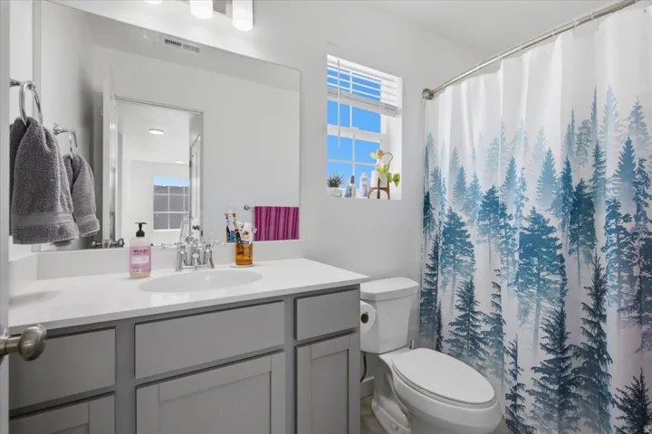 Vanity with an integrated sink and chrome faucet, gray cabinetry, and a large wall mirror