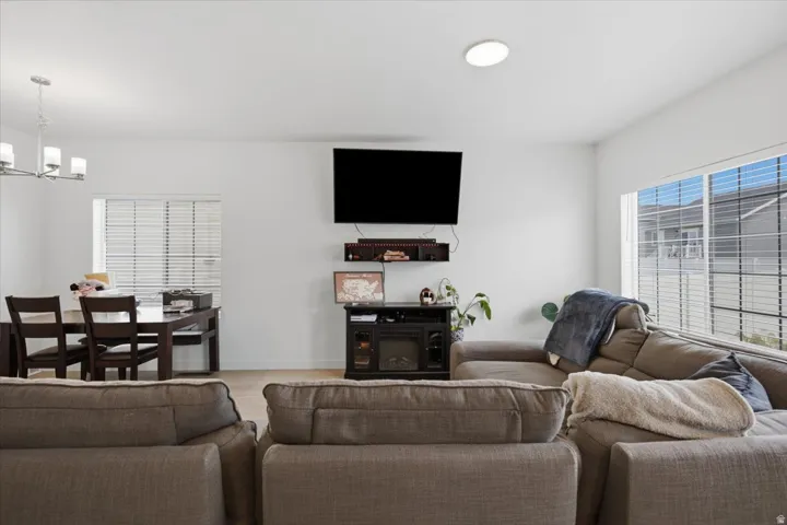 Open-concept living area featuring light wood-finish flooring, white walls, and horizontal window blinds