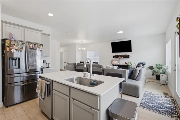 Kitchen island with an undermount sink, a stainless steel dishwasher, and light-toned cabinetry