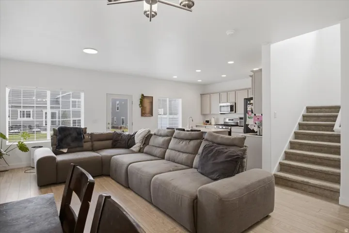 Open-concept living space featuring wood-finish flooring, recessed lighting, a modern kitchen, and a carpeted staircase