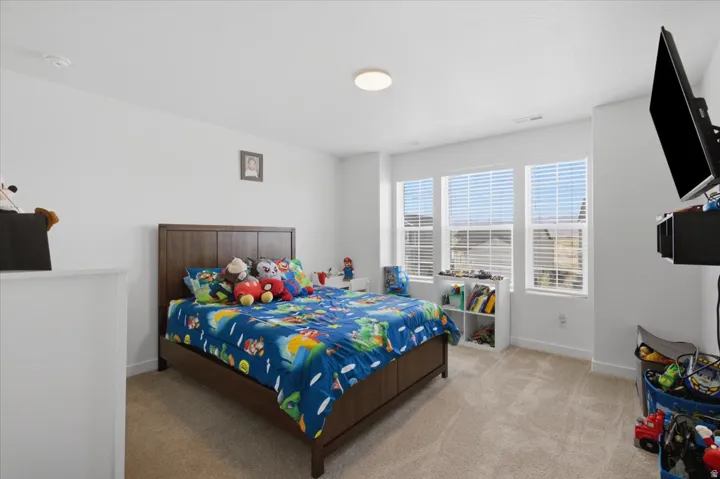 Light beige carpeting, a large ceiling light fixture, and three bright windows with blinds