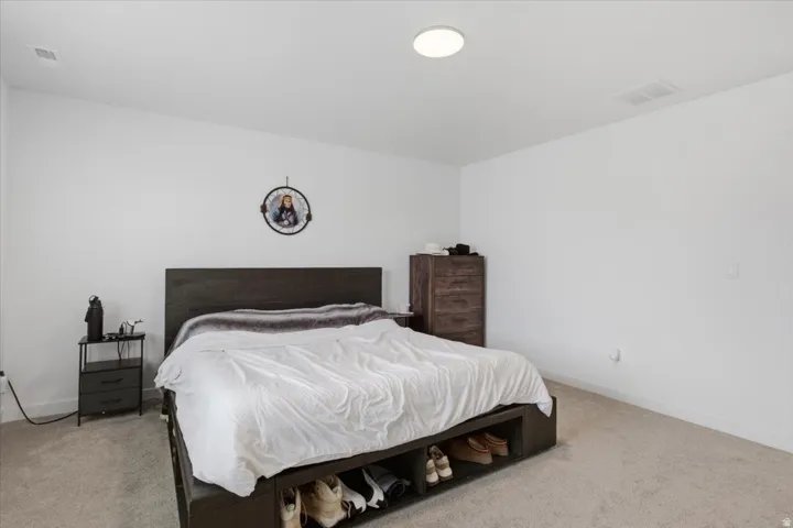 Master bedroom featuring neutral white walls, recessed ceiling light, and light-toned carpet
