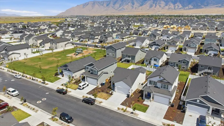 Residential community featuring single-family homes, paved streets, and a central green space with a playground