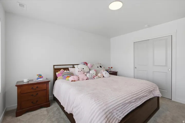 White painted walls, light-colored carpeting, recessed lighting, and a bi-fold closet door