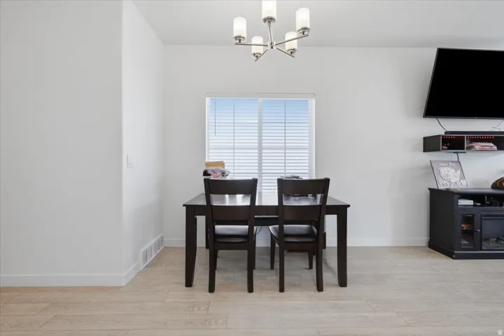 Recessed window with horizontal blinds, overhead chandelier light fixture, and wood-finish flooring