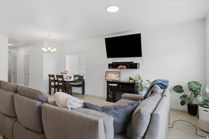 Open-concept living area featuring a neutral-toned sectional sofa, wall-mounted flat-screen television, and entertainment cabinetry with shelving
