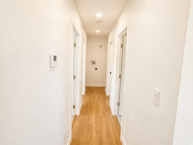 Hallway featuring wood-finish flooring, recessed lighting, and a neutral color palette