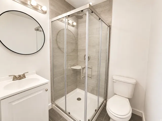 Walk-in shower with clear glass enclosure and tile surround