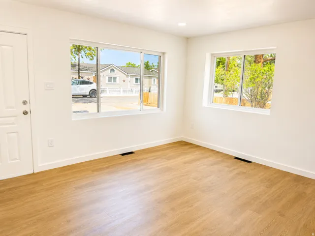 Recessed ceiling lighting, wood-finish flooring, white trim, and multiple windows