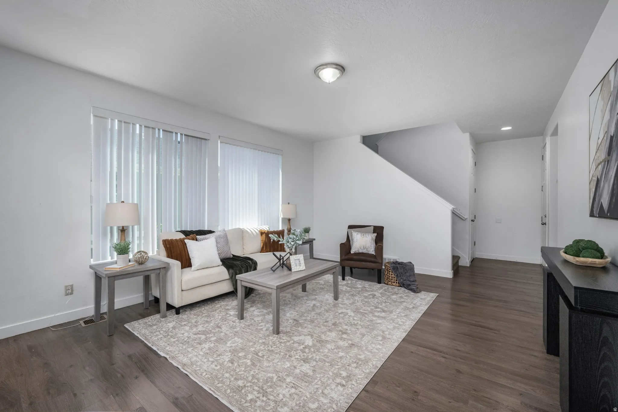 Recessed ceiling lighting, wood-finish flooring, white walls, and a staircase with a white railing