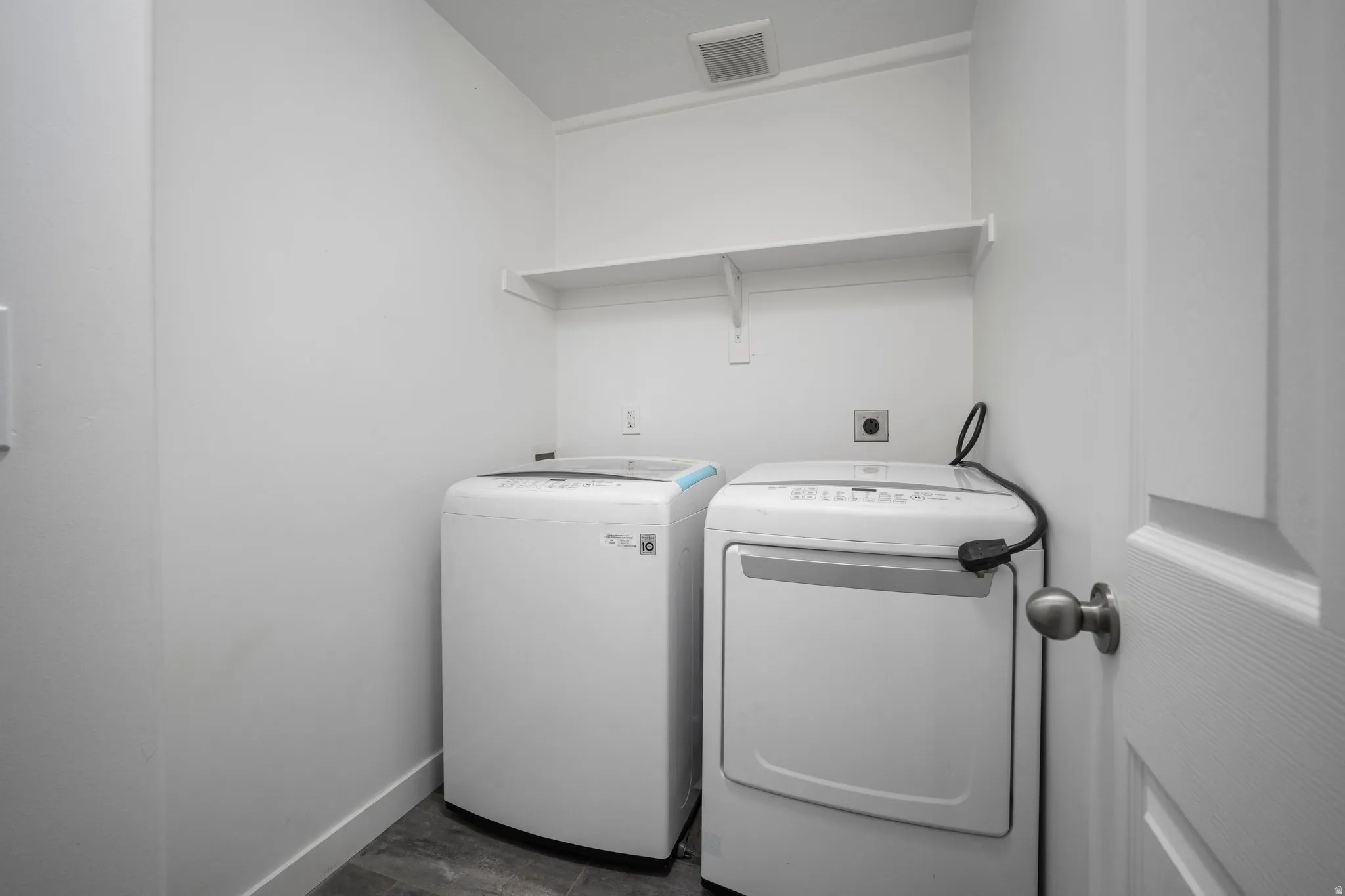 Dedicated laundry area featuring a built-in white shelf and grey-toned flooring