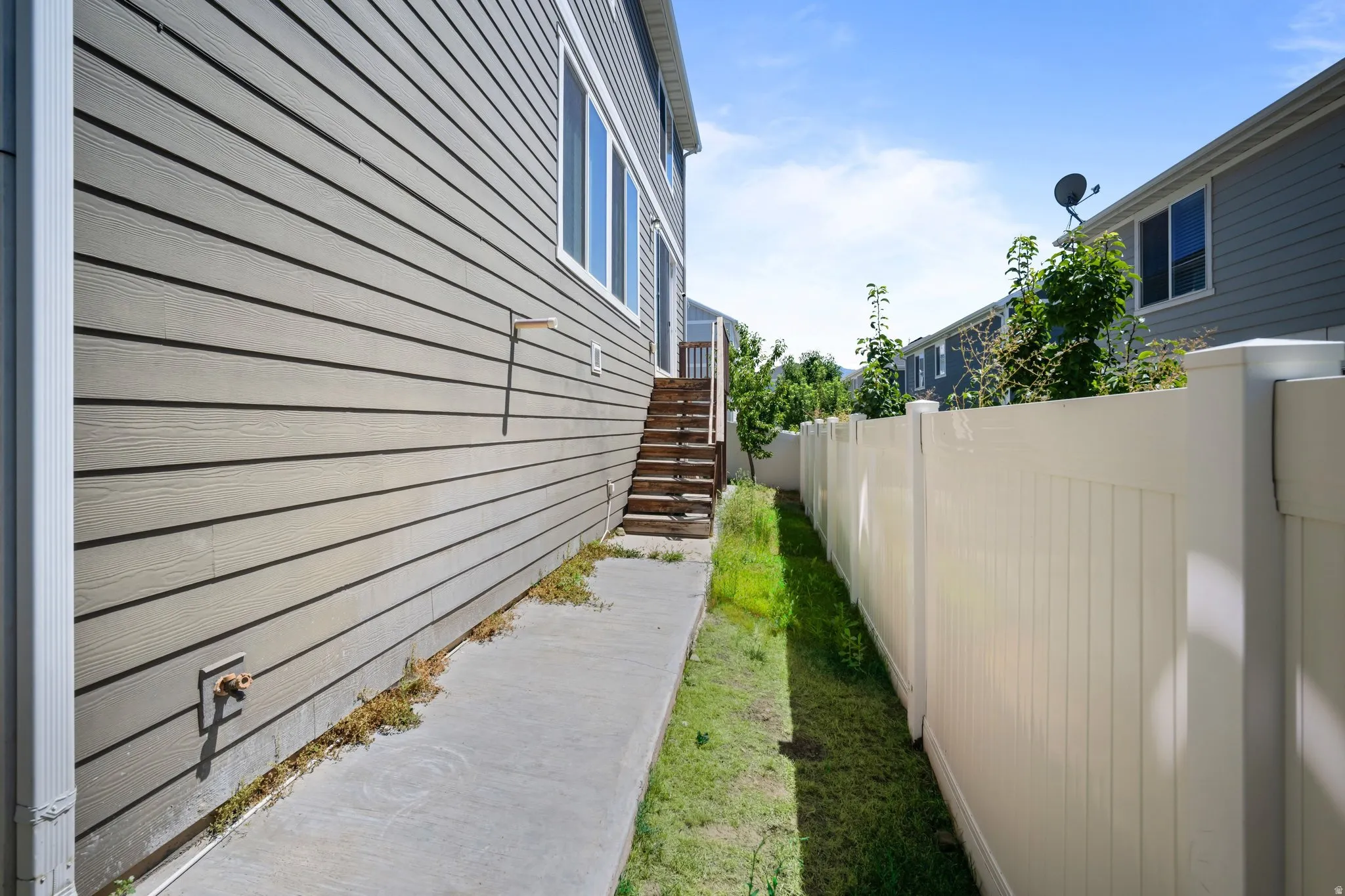 Exterior featuring horizontal siding, multiple windows, and a concrete pathway