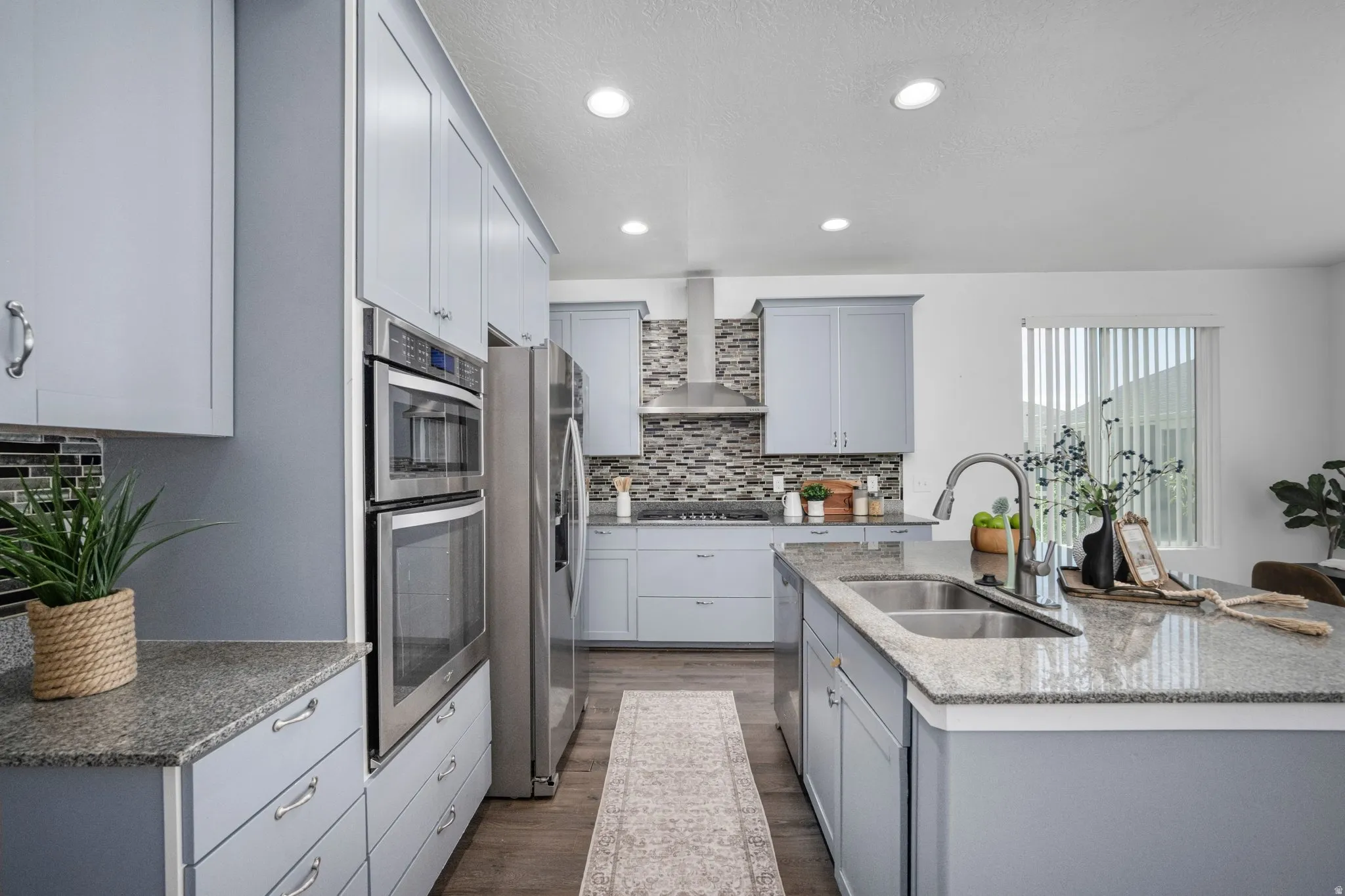 Contemporary kitchen featuring light blue cabinetry, stainless steel appliances, speckled countertops, a tile backsplash, and recessed lighting