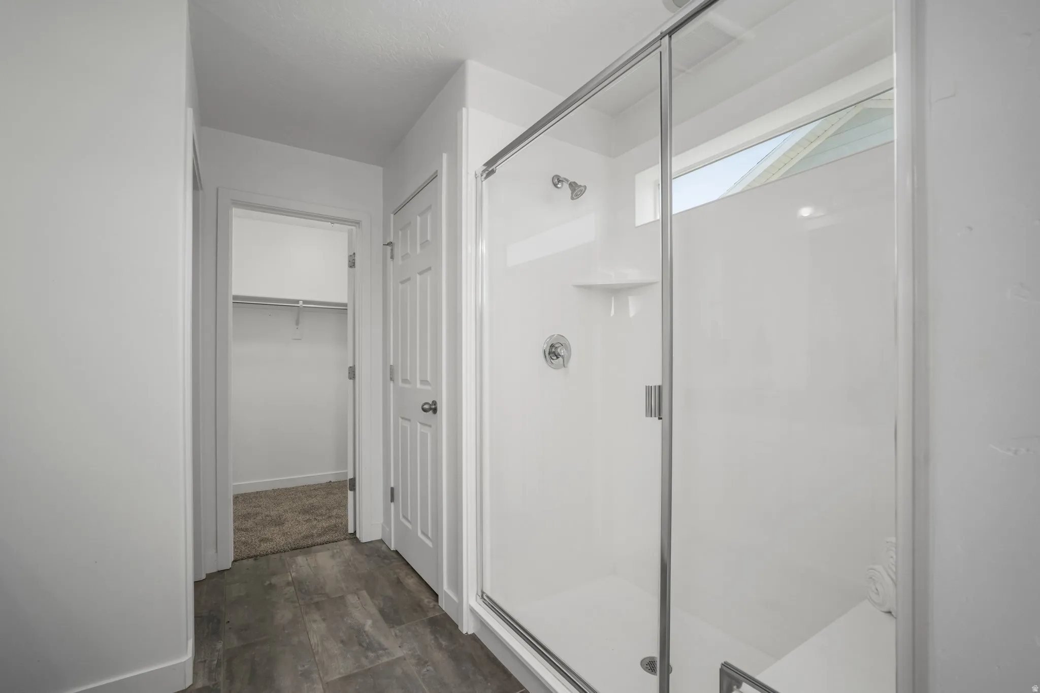 Walk-in shower with clear glass enclosure, integrated corner shelf, and built-in bench