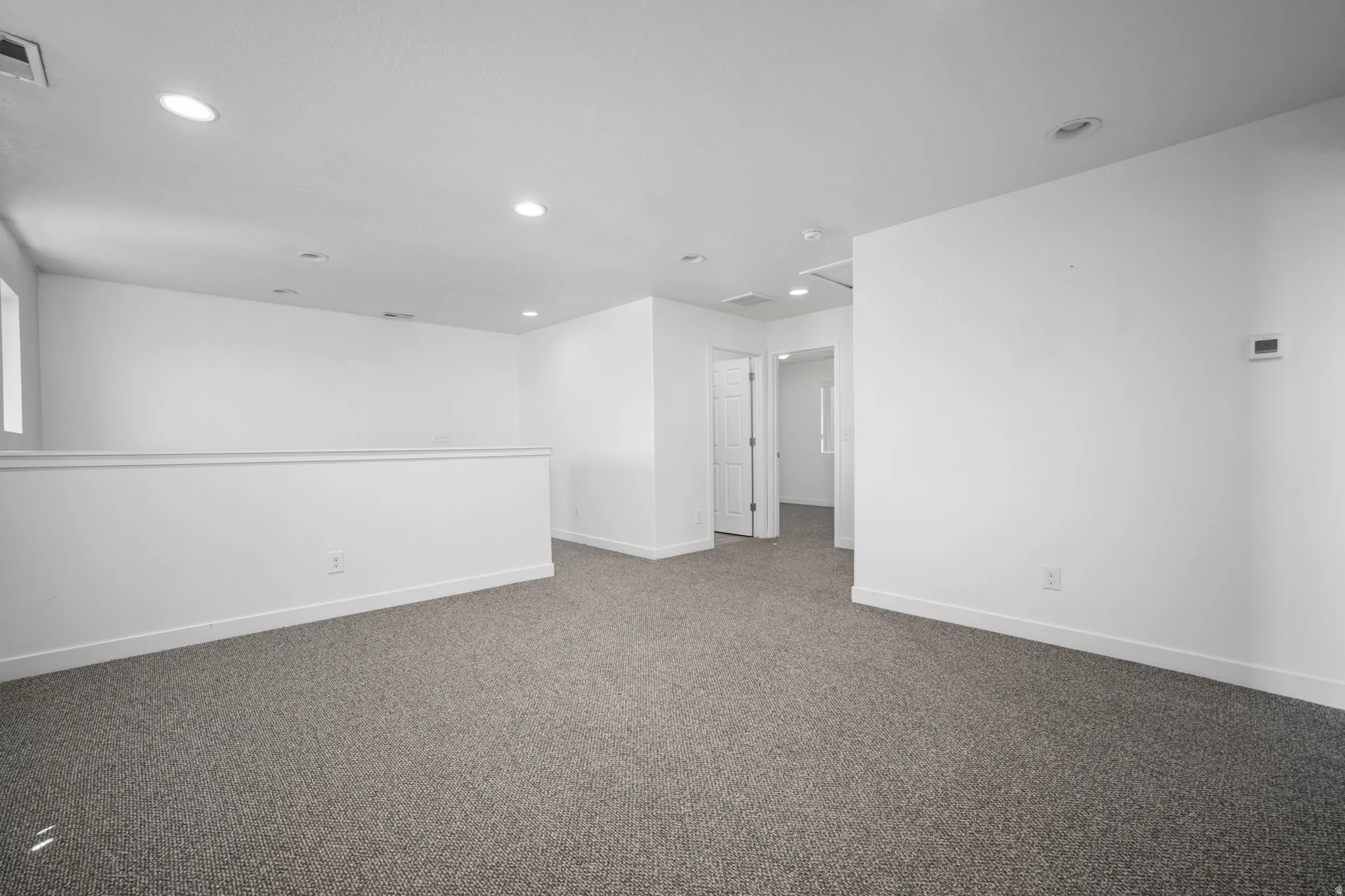 Recessed ceiling lighting, white interior doors, and neutral carpeting
