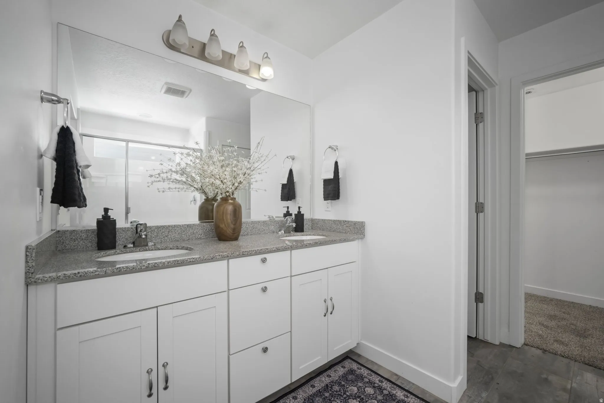 Dual vanity with undermount sinks, granite-finish countertop, and white shaker-style cabinetry