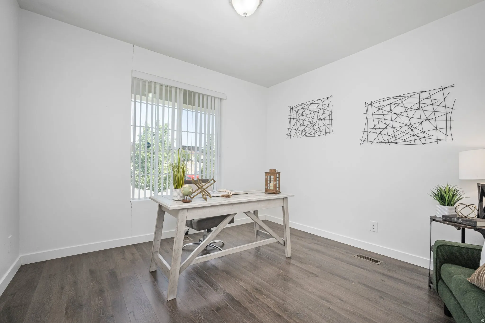 Bright room with wood-finish flooring and a large window featuring vertical blinds
