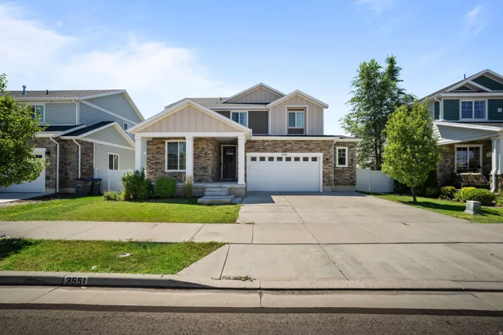 Two-story residence featuring a stone and siding exterior, an attached two-car garage, and a front porch with columns