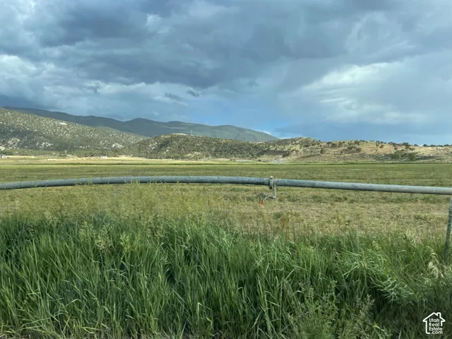 Expansive field with a metal irrigation pipe, surrounded by distant mountains