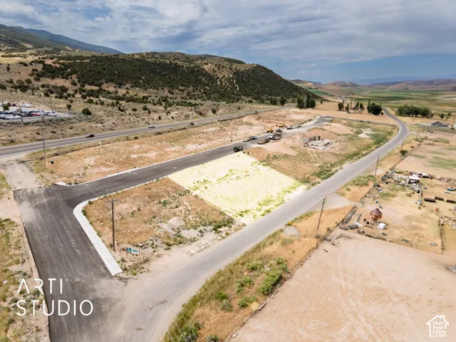 Expansive undeveloped lot featuring paved road access, adjacent to a paved highway, and surrounded by mountainous terrain