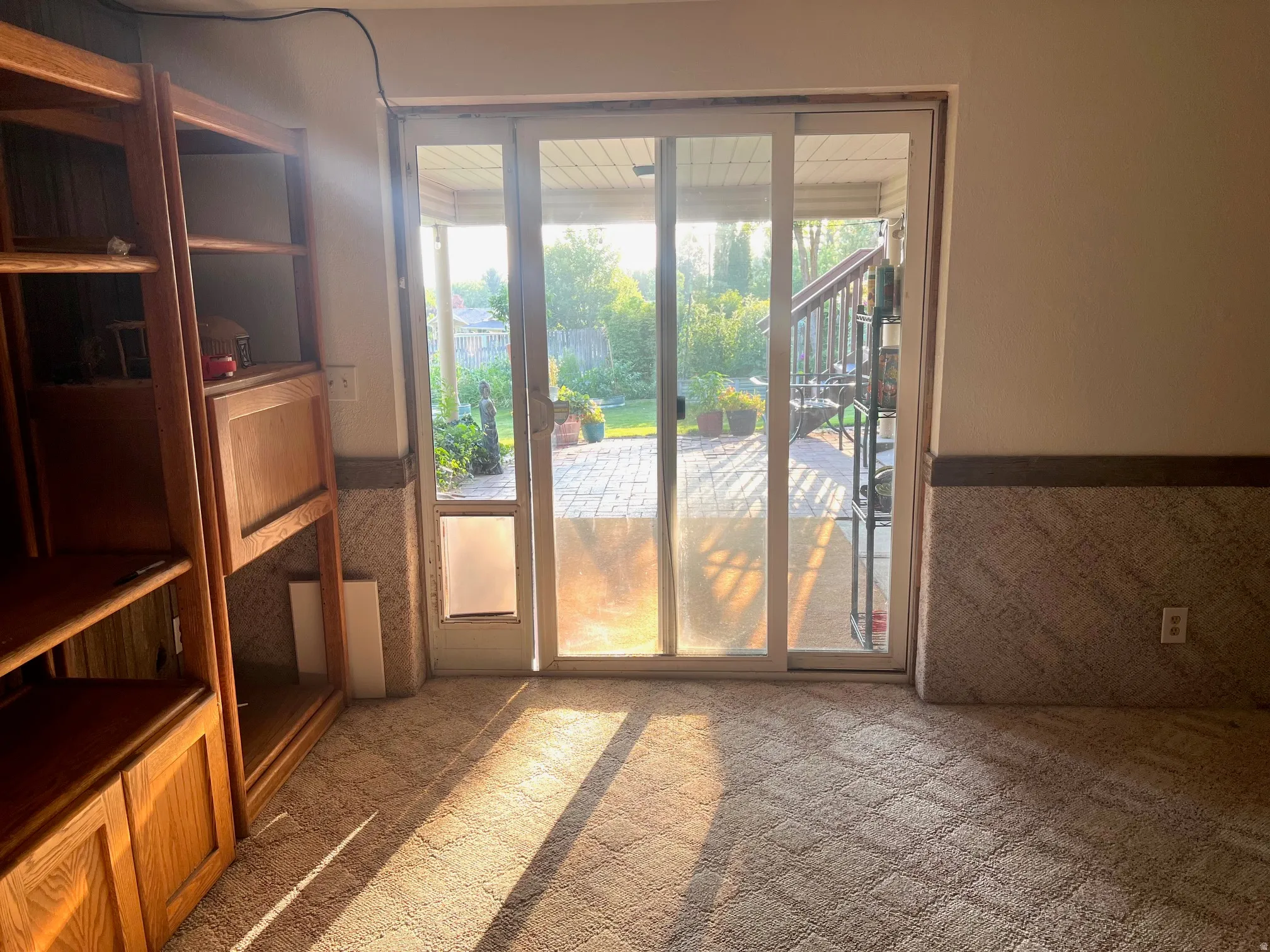 Built-in wood-finish shelving with cabinetry, patterned carpet flooring, and a sliding glass door