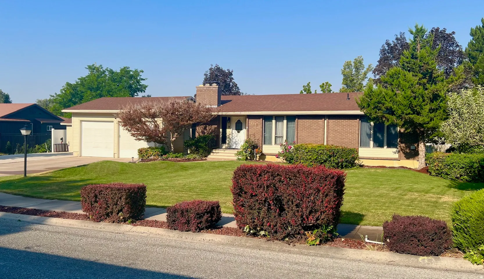 Ranch-style residence featuring a brick facade, attached garage, and a central entry with steps