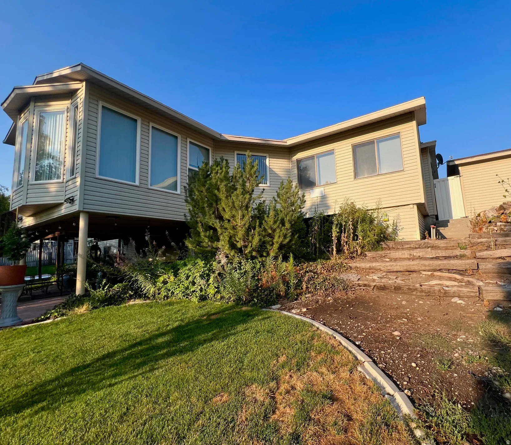 Exterior siding finish, multiple large windows, bay window, sloped roofline, terraced landscaping