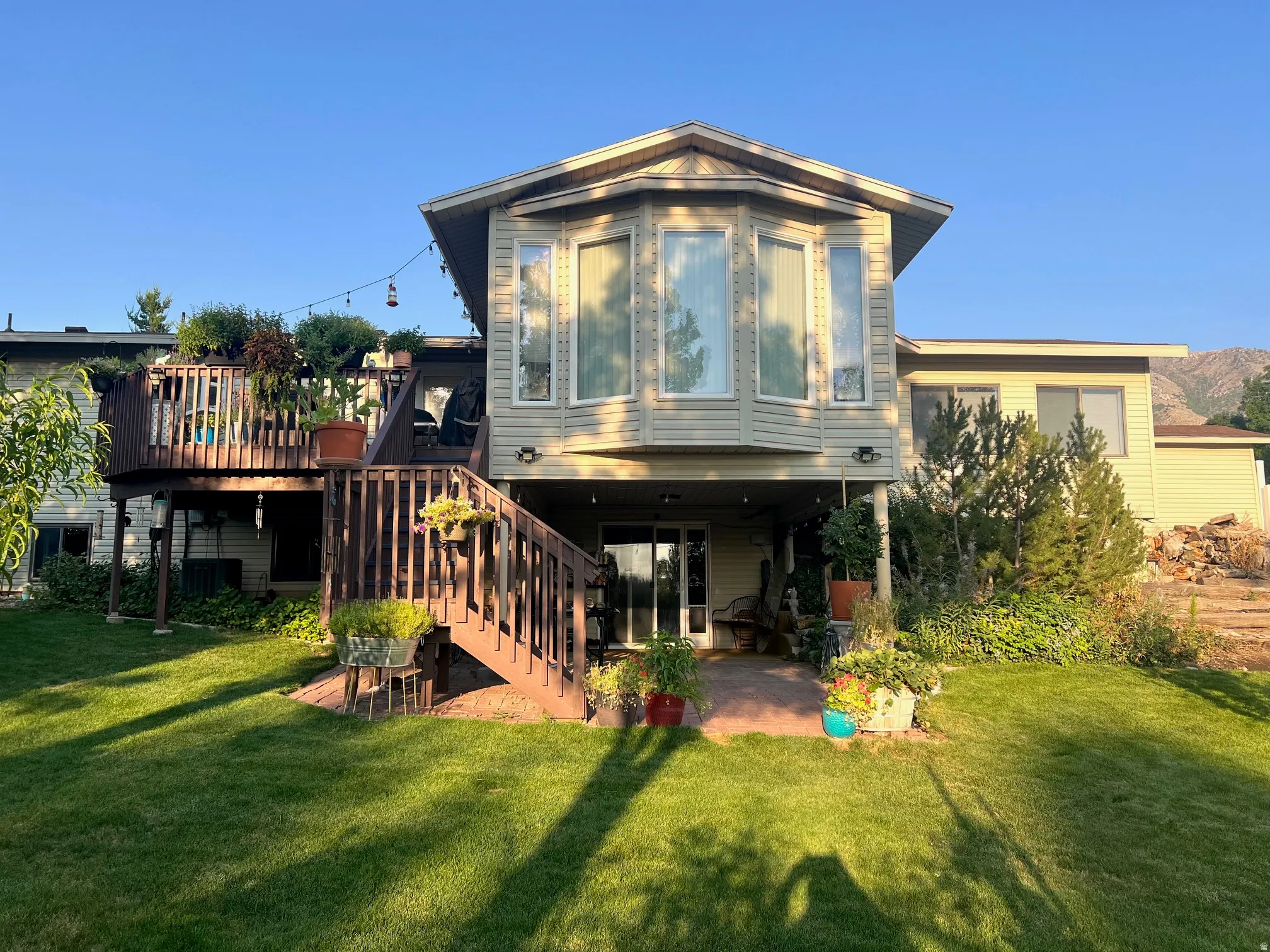 Elevated residence featuring expansive windows and a modern bay-style upper level, situated above a covered ground-level entry