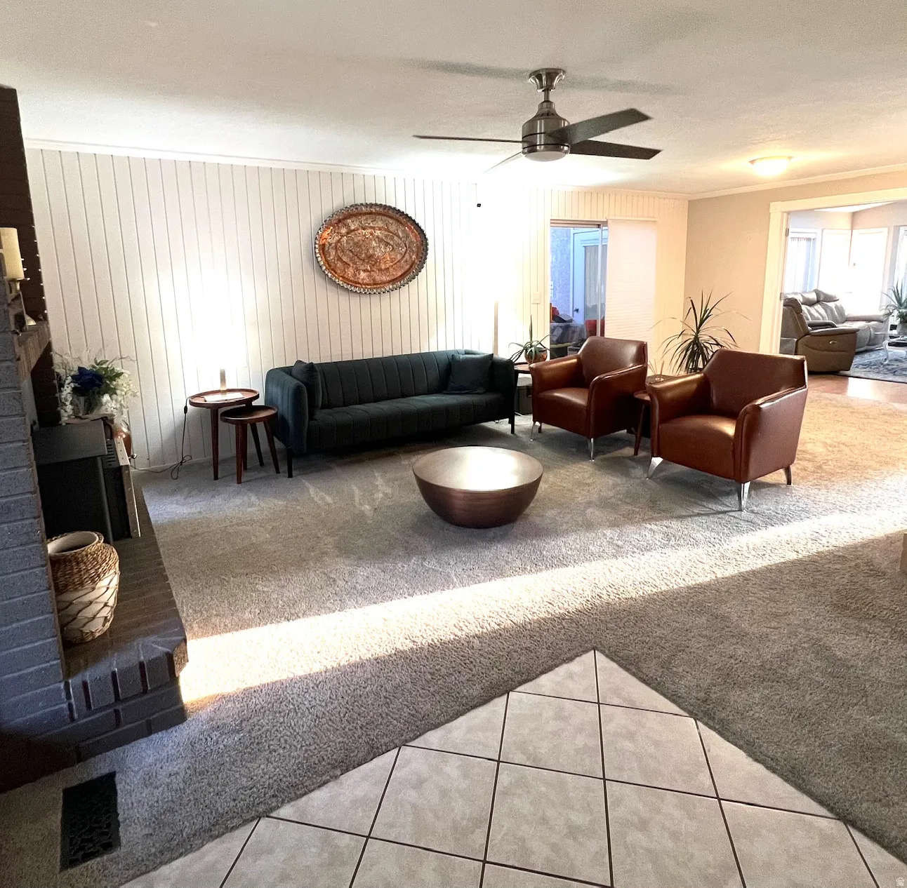 Spacious living area featuring a black mid-century sofa, cognac leather armchairs, and a sculptural metal coffee table anchoring the room