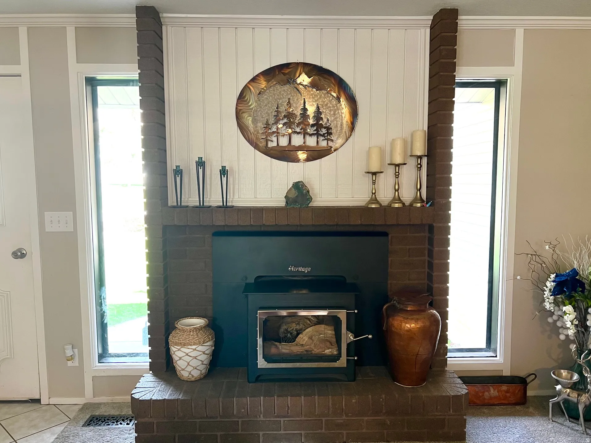 Brick fireplace with a black wood-burning stove insert, flanked by two vertical windows, and a white beadboard accent wall