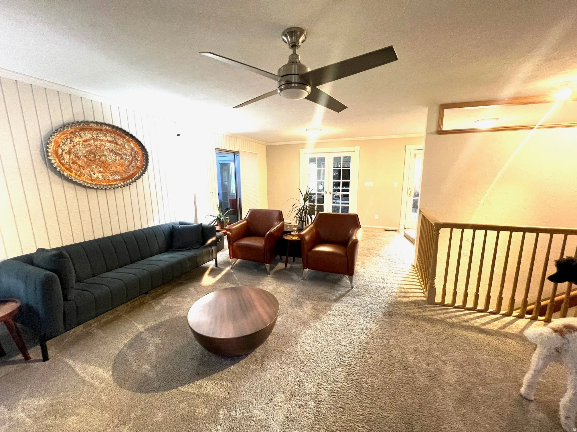 Spacious open-concept living area featuring a curved sectional sofa, paired burgundy accent chairs, and a sculptural round coffee table