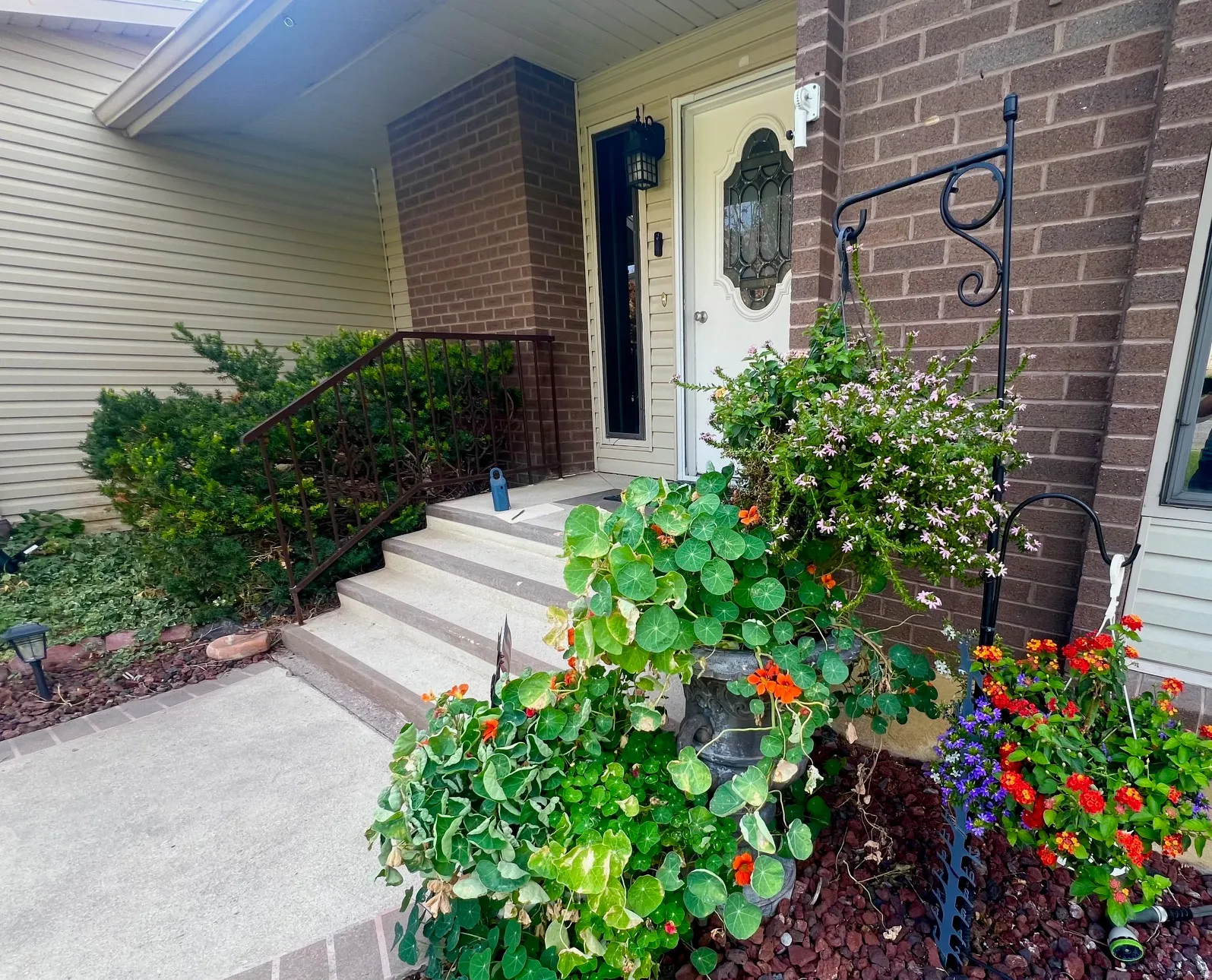 Entryway featuring concrete steps with wrought iron railing, brick facade, and a white entrance door with decorative glass